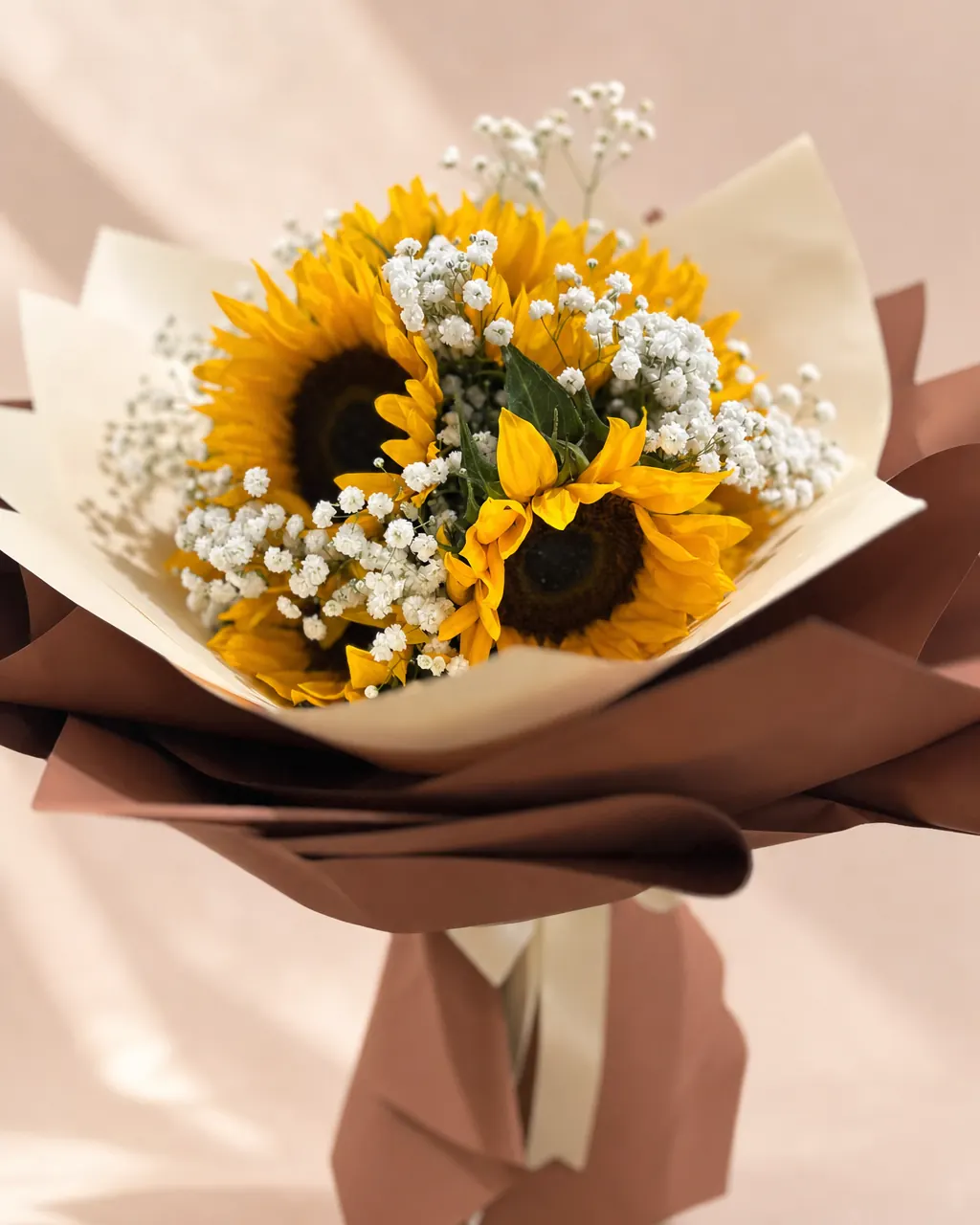 Caramel Sun: sunflowers with baby's breath in cream and caramel wrap, on a blush backdrop